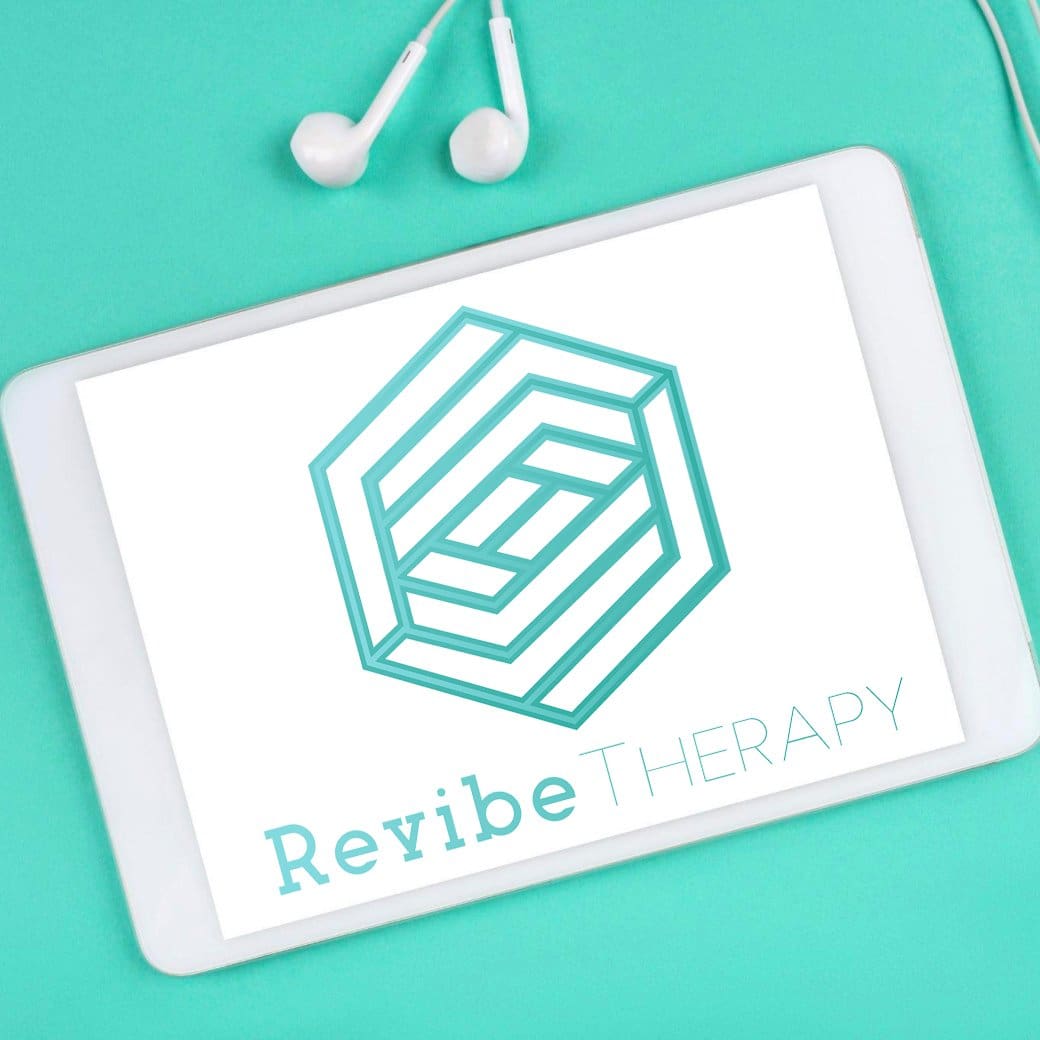 A tablet displaying the logo for Revibe Therapy, which features a geometric design and the text “Revibe Therapy.” Earphones are placed beside the tablet, all set against a teal background. revibe therapy logo on tablet for those looking for an online therapist, online therapy or online hypnosis