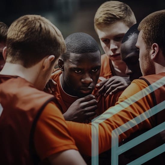 Five basketball players in red jerseys are huddled together, exhibiting focus and determination. The central player, who is surrounded by his teammates, shows intense concentration. The scene is dramatic, capturing a moment of unity and strategy.