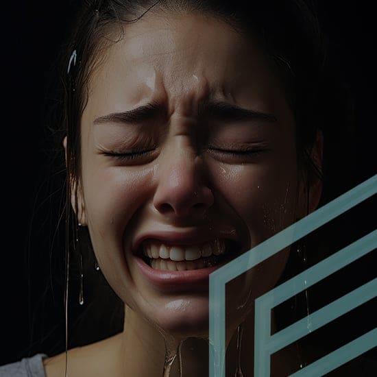 A person with wet hair and water droplets on their face appears distressed, with eyes closed, mouth open, and eyebrows furrowed. A translucent geometric shape overlays part of the image. Dark background contrasts with the person's expressive face.