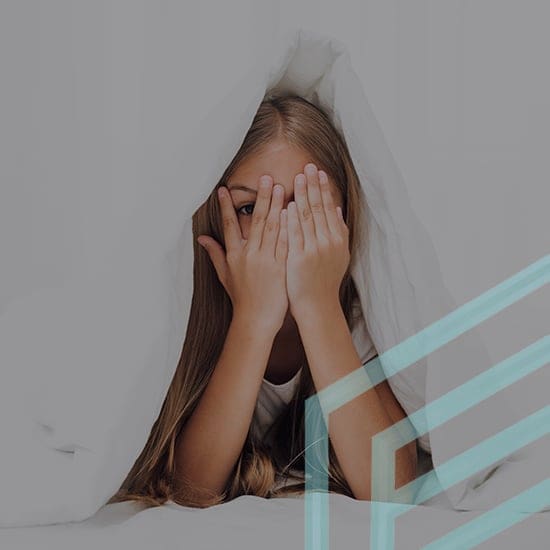 A child with long hair lies under a white blanket, peeking through their fingers while covering their face. The surroundings are a soft, neutral background. A translucent geometric design overlays part of the image on the right side.