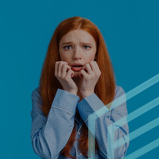 A red-haired woman in a polka-dot shirt stands against a solid blue background, looking anxious with her hands near her mouth and furrowed eyebrows. Pale blue geometric lines are overlaid on the image.