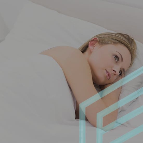 A person with light hair is lying in bed, their head resting on a pillow, and looking upwards. They are covered with a white blanket. The image has a geometric pattern overlay on the right side.