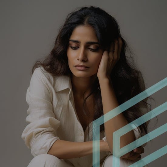 A woman with long, wavy hair sits while resting her head on her hand. She wears a light-colored shirt and appears to be in deep thought or contemplation. The background is neutral, and there is a geometric design overlay in the corner of the image.